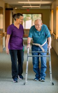 Nurse helping an elderly man on his walker